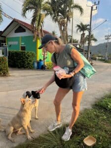 Woman feeding street dogs in Thailand
